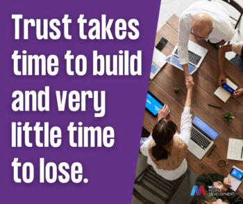 Quote graphic with bold white text on a purple background reading "Trust takes time to build and very little time to lose" beside an overhead photo of two people shaking hands across a table with laptops and notebooks, with the Mosaic People Development logo in the bottom right corner.